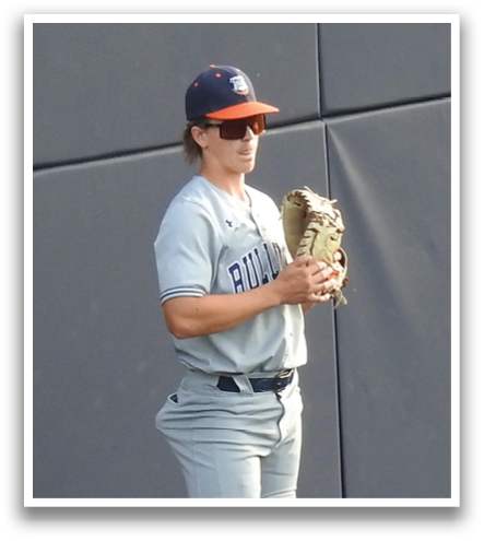A man wearing a baseball shirt stands on a baseball field. Contenido generado con IA