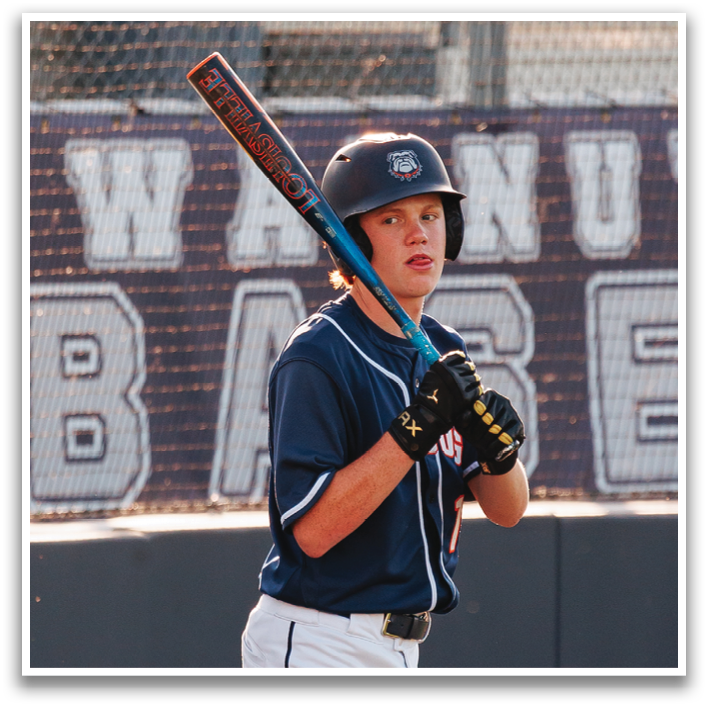 A baseball player in a blue and white uniform stands on the field holding a bat, ready to play. Contenido generado con IA