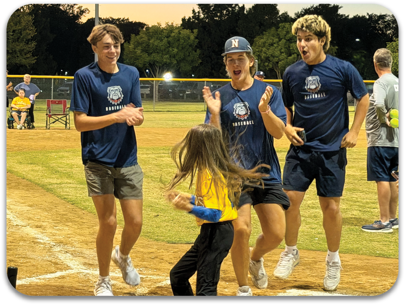 Three young men are playing baseball on a field. A young girl is standing in front of them, and they are all laughing and having a good time. Contenido generado con IA