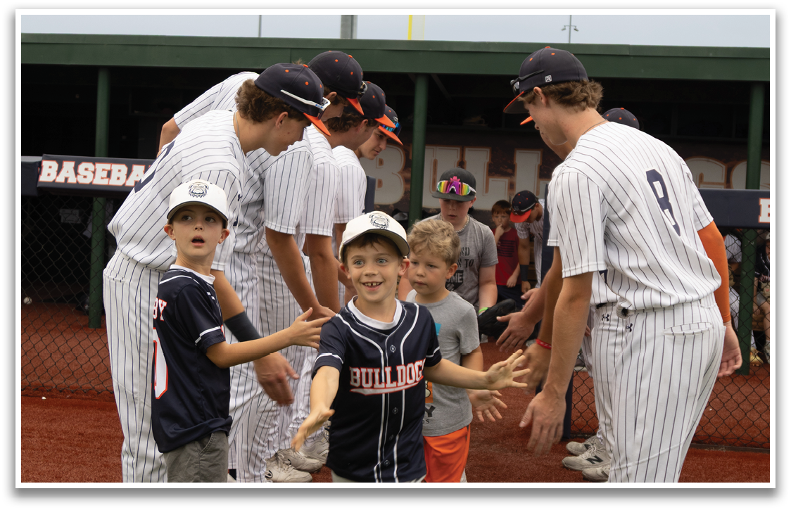 A group of young boys are on a baseball field, shaking hands with a group of older men. Contenido generado con IA