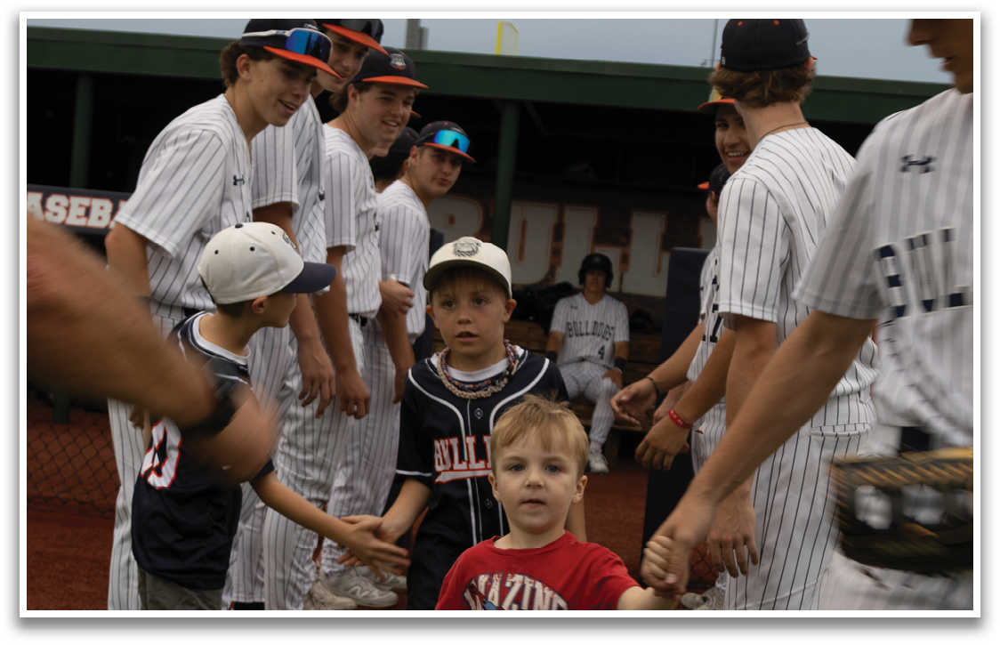 A group of young baseball players are standing on a field, with one boy holding hands with another boy. Contenido generado con IA