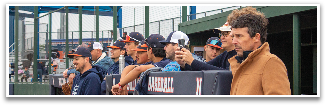 A group of men are standing in front of a fence, watching a baseball game. Contenido generado con IA