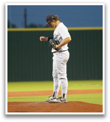 A baseball player is standing on the pitcher's mound, wearing a baseball uniform and a cap. Contenido generado con IA