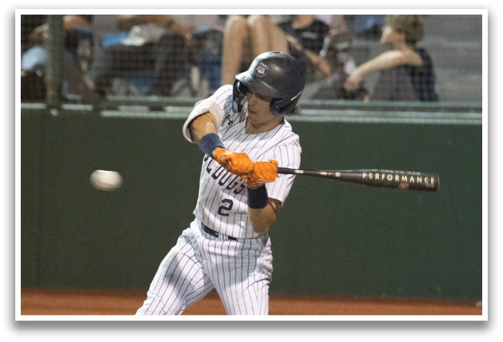 A baseball player is swinging a bat at a ball, with the ball in the air and the player in the process of hitting it. There are several other people in the scene, some of whom are sitting on chairs and watching the game. Contenido generado con IA
