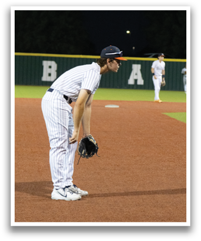 A baseball player is crouching on the field, wearing a baseball glove. Another player is standing in the background. Contenido generado con IA