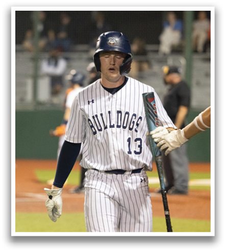 A baseball player wearing a blue helmet and a white jersey with the number 13 walks across the field. Contenido generado con IA