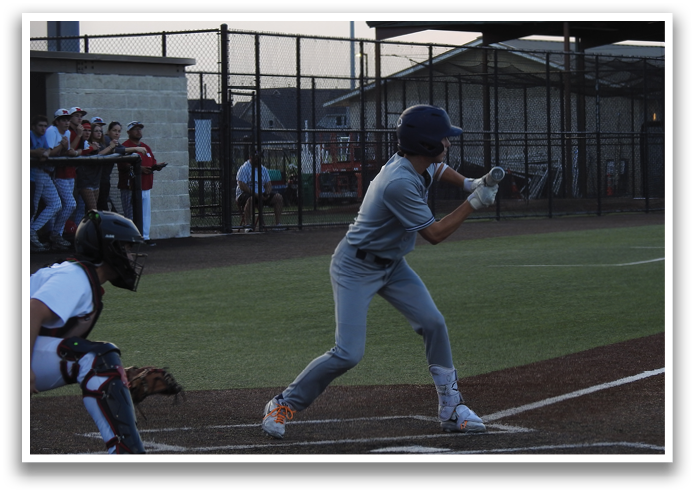 A baseball player in a grey uniform is swinging a bat, attempting to hit a ball. Contenido generado con IA