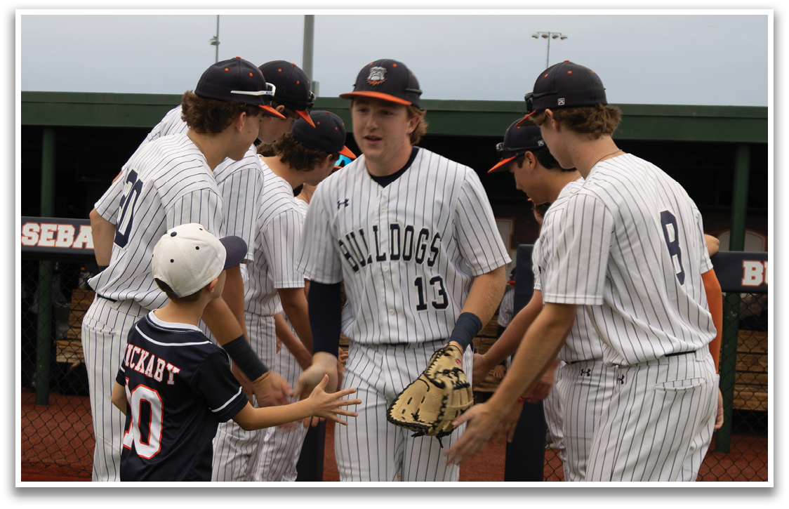 A group of baseball players and a young boy are standing on a field. Contenido generado con IA