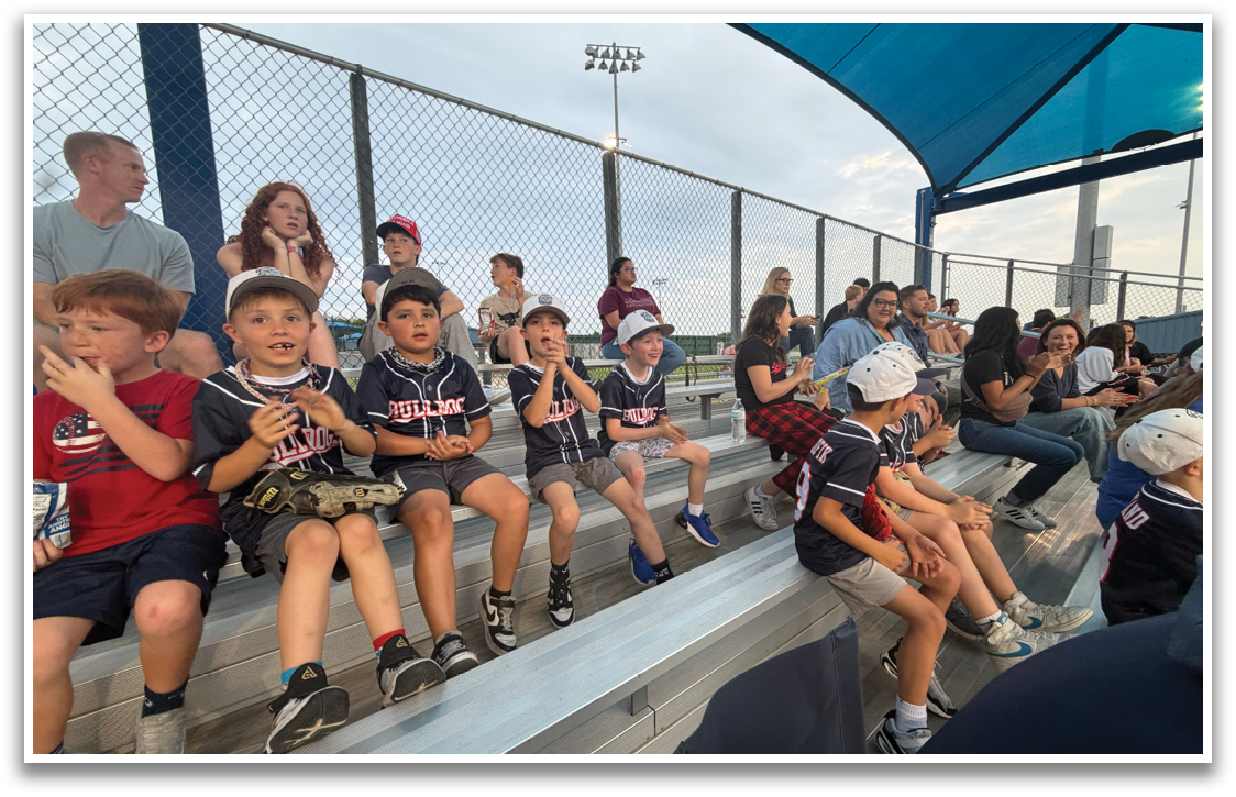 A group of children are sitting on a bench at a baseball game. Contenido generado con IA