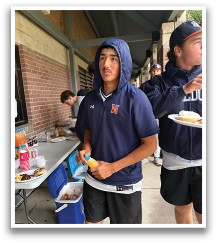 A man wearing a blue hoodie is holding a banana and an orange. Contenido generado con IA
