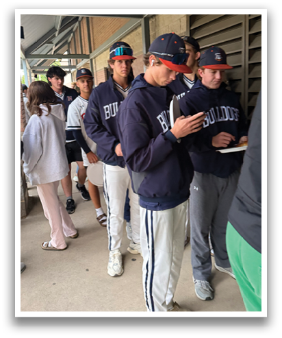 A group of people are standing outside, some of them wearing baseball caps. One person is holding a cell phone. Contenido generado con IA