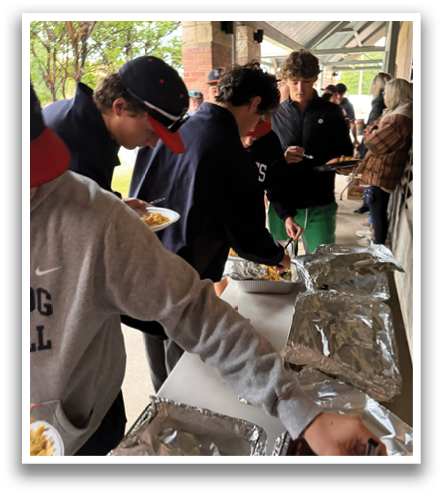 A group of people are standing around a table with food. Contenido generado con IA