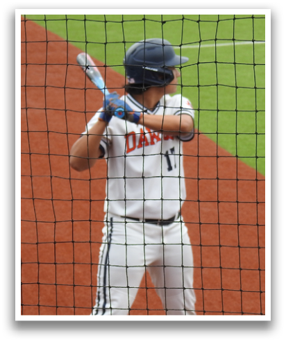 A baseball player in a white uniform is holding a bat and preparing to swing at a pitch. Contenido generado con IA
