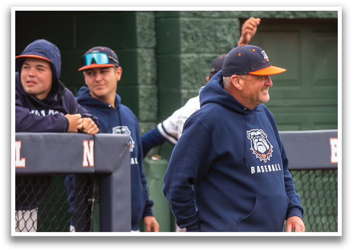 A man wearing a blue baseball cap and a blue jacket is walking on a baseball field. Contenido generado con IA