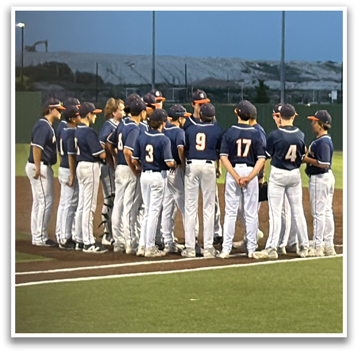 A baseball team is standing on the field, wearing blue and white uniforms. They are lined up, facing the same direction, and appear to be listening to their coach. Contenido generado con IA