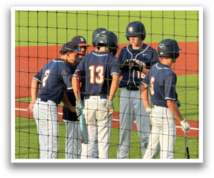 Four baseball players wearing blue and orange uniforms are standing together on the field. Contenido generado con IA