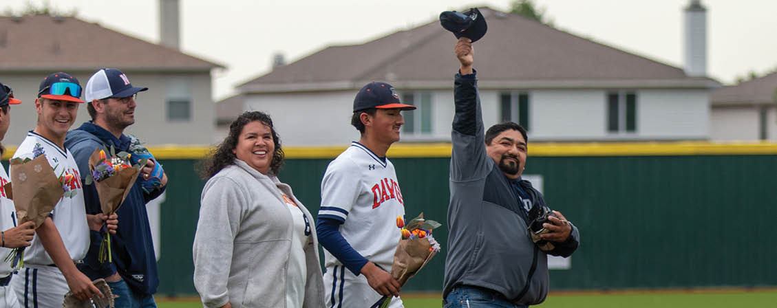 A group of people, including baseball players, are standing on a field. Contenido generado con IA