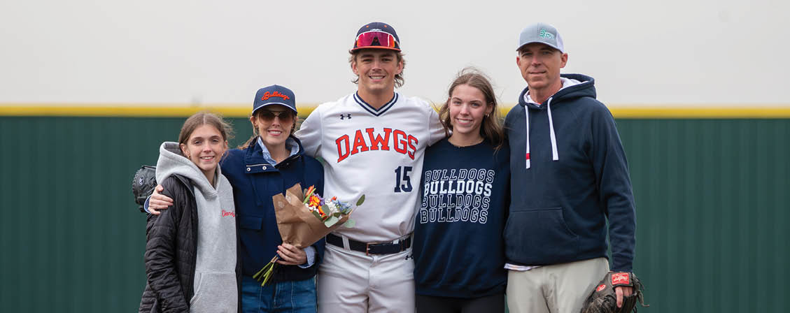 A group of people, including a baseball player, pose for a photo on a baseball field. Contenido generado con IA