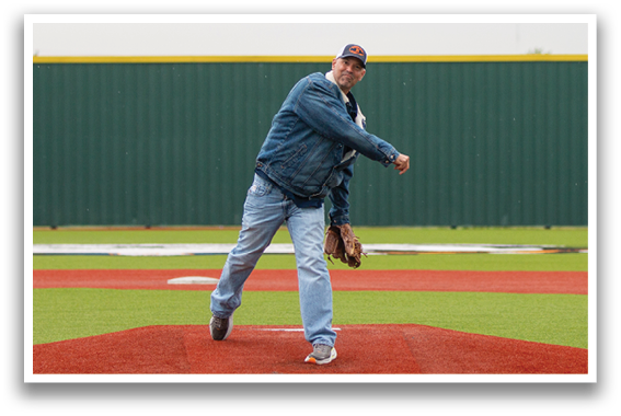 A man is throwing a baseball on a field, with a woman watching nearby. Contenido generado con IA
