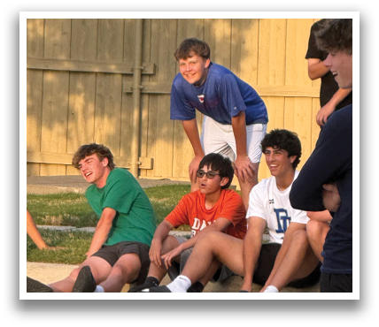 A group of young boys are sitting on the ground outside. Contenido generado con IA