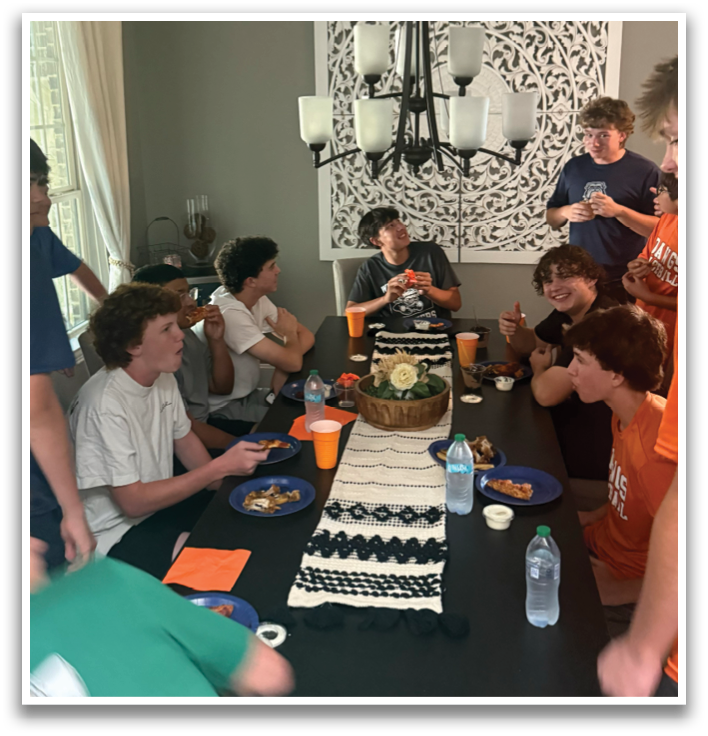 A group of people are sitting around a dining table, enjoying a meal together. Contenido generado con IA