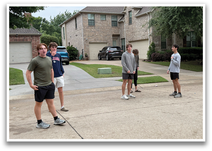 Four young men are standing in a driveway, playing a game of frisbee. Contenido generado con IA