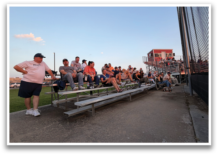 A group of people are sitting on a bench in a field. Contenido generado con IA