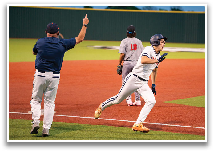 A baseball player is running towards home plate, while a coach watches from the sidelines. Contenido generado con IA