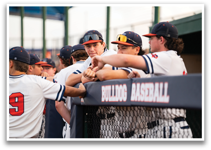 Baseball players wearing blue and white uniforms are gathered around a fence. Contenido generado con IA