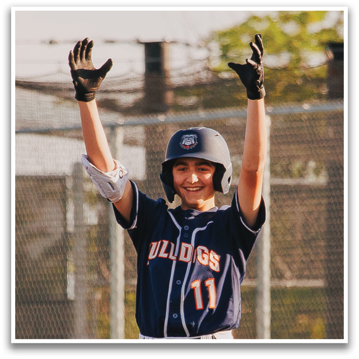 A baseball player wearing a blue and white uniform is standing on home plate, holding his arms up in the air. Contenido generado con IA
