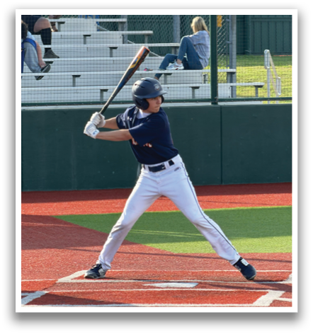A baseball player is at bat, holding a bat and waiting for the pitch. The catcher is positioned behind him, wearing a baseball glove. There are several other people in the scene, some of whom are sitting on a bench. Contenido generado con IA