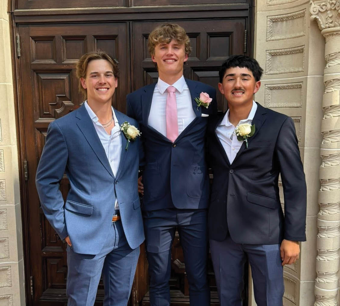 Four young men in suits and ties pose for a picture. Contenido generado con IA
