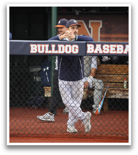 Baseball players are standing on the field, with one player leaning on the fence. Contenido generado con IA