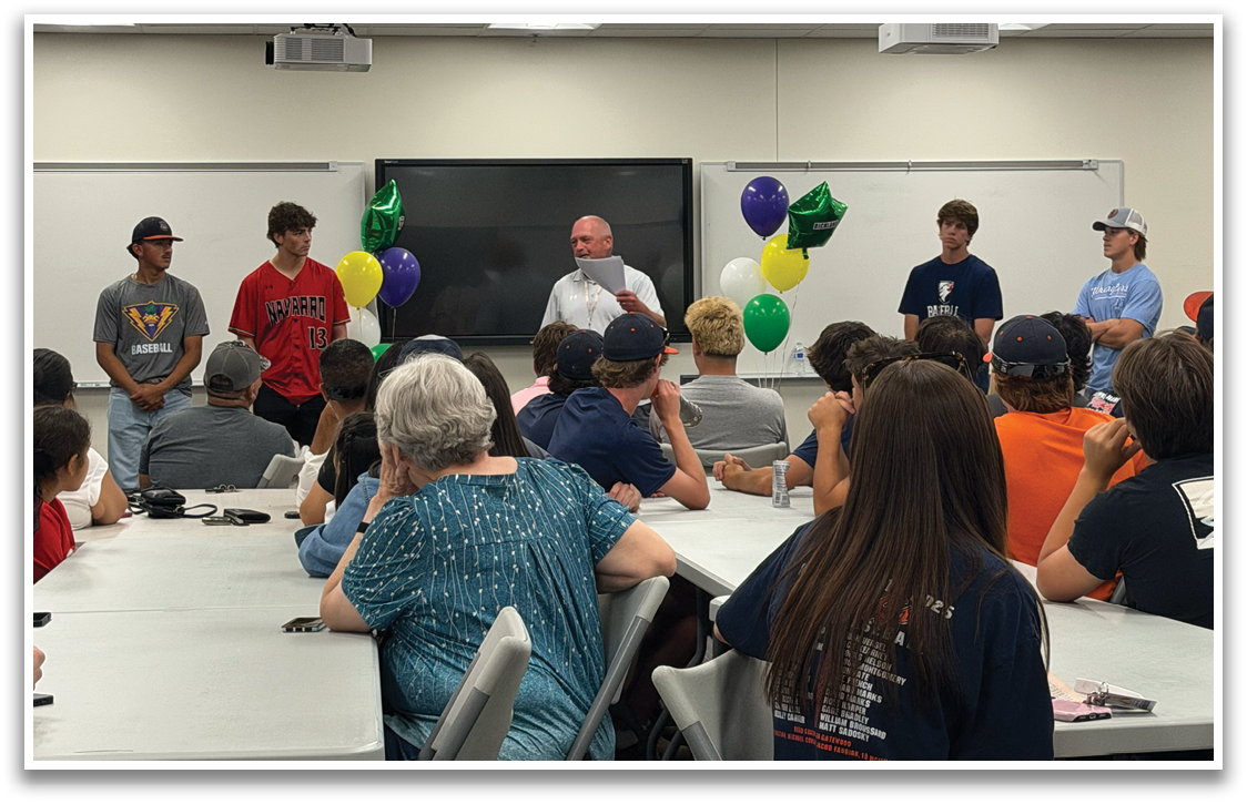 A group of people are standing in front of a classroom, with balloons and a TV behind them. They are likely giving a presentation or speech. Contenido generado con IA