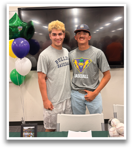 Two young men pose for a picture in front of a table with baseballs on it. Contenido generado con IA