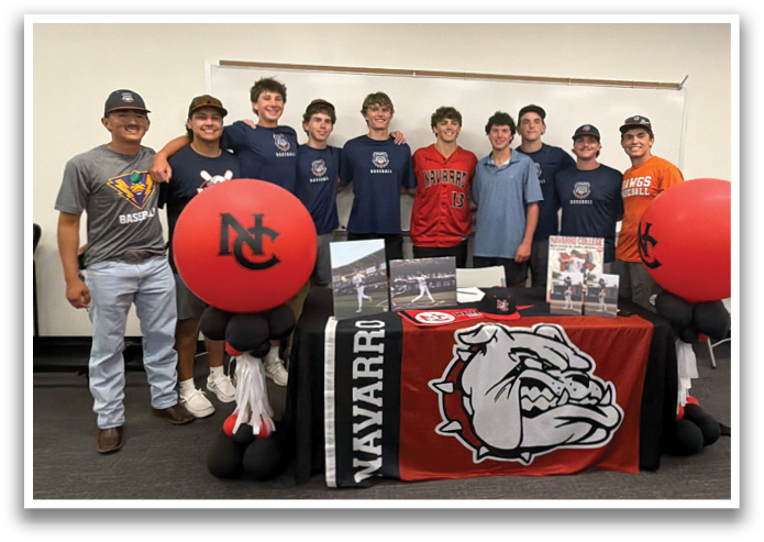 A group of young men pose for a picture in front of a table with a red and white bull dog mascot. Contenido generado con IA