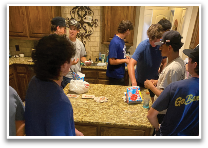 A group of people are gathered in a kitchen, standing around a counter. They are engaged in conversation and enjoying each other's company. Contenido generado con IA