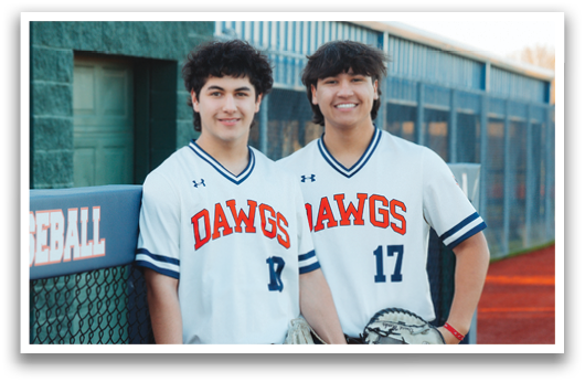 Two young men wearing baseball uniforms and holding baseball gloves. Contenido generado con IA