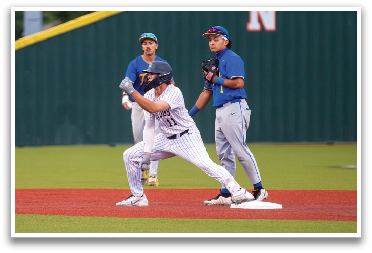 A baseball player wearing a blue shirt and grey pants is running to a base. Contenido generado con IA