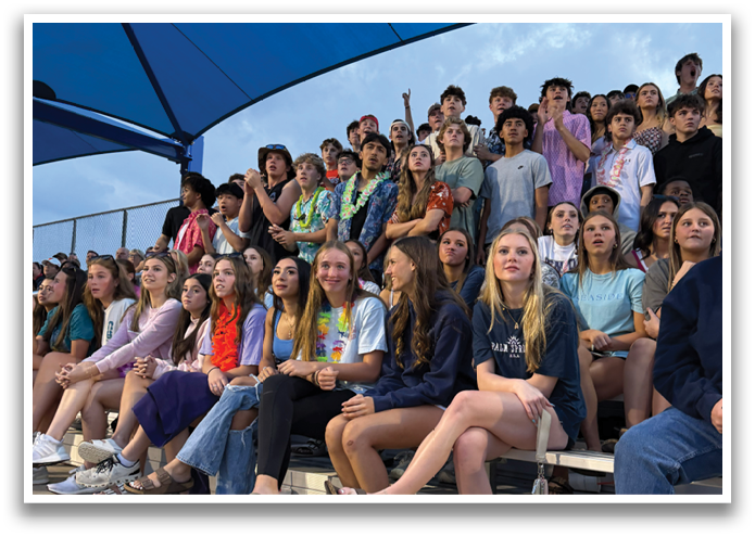 A group of people are sitting on a bench, watching a game. Contenido generado con IA
