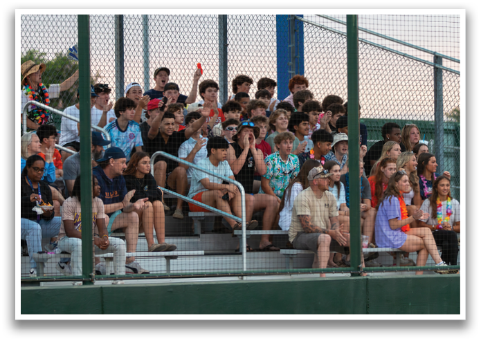 A group of people are sitting on a bleacher, watching a baseball game. Contenido generado con IA