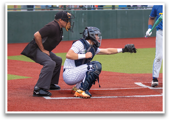 A baseball player is holding a bat, ready to swing at a pitch. The catcher is kneeling behind him, wearing a baseball glove. Contenido generado con IA