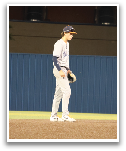 A baseball player stands on a field, wearing a blue shirt and holding a baseball glove. Contenido generado con IA