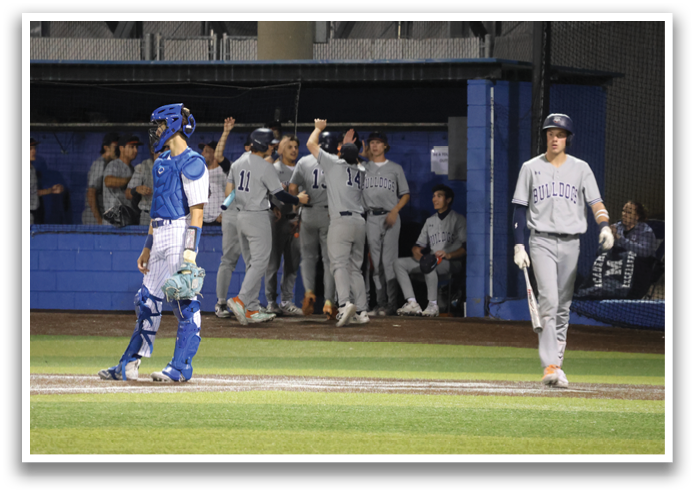 A baseball game is in progress with players on the field. A man in a blue shirt is walking away from the field while another player is walking towards it. The players are wearing baseball gloves and the scene is set on a baseball field. Contenido generado con IA