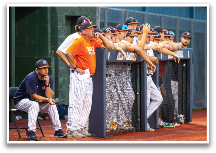 Baseball players are lined up behind a fence, waiting for their turn to play. Contenido generado con IA