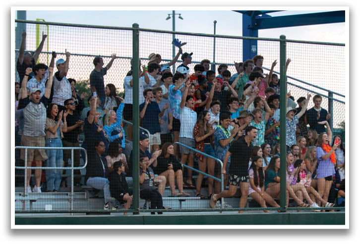 A large group of people are sitting in the bleachers, watching a game. Contenido generado con IA