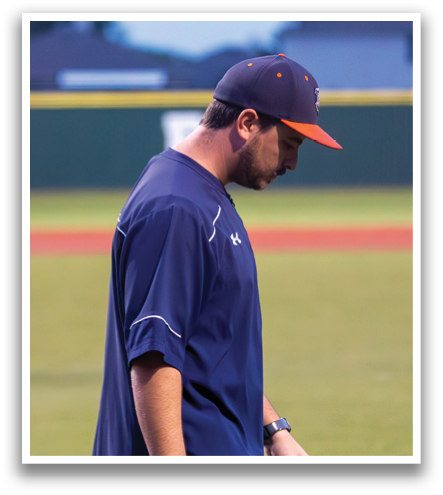 A man wearing a blue shirt and a baseball cap stands on a baseball field. Contenido generado con IA