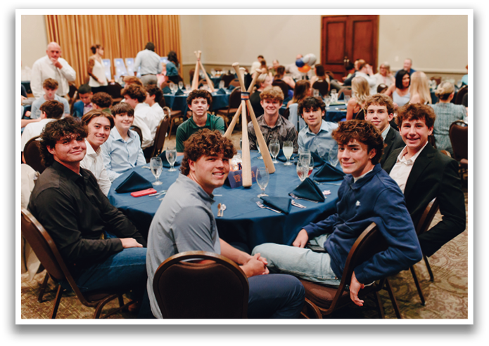 A group of young men and women are sitting around a table, smiling and posing for a picture. Contenido generado con IA