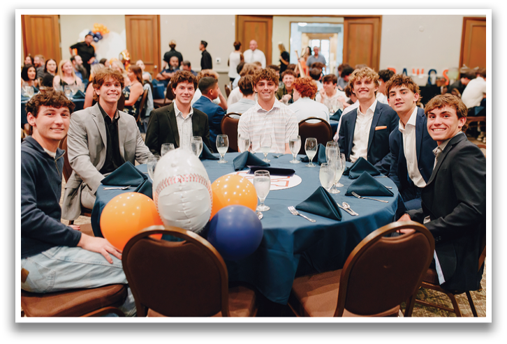 A group of young men are sitting around a table with a balloon on it. Contenido generado con IA