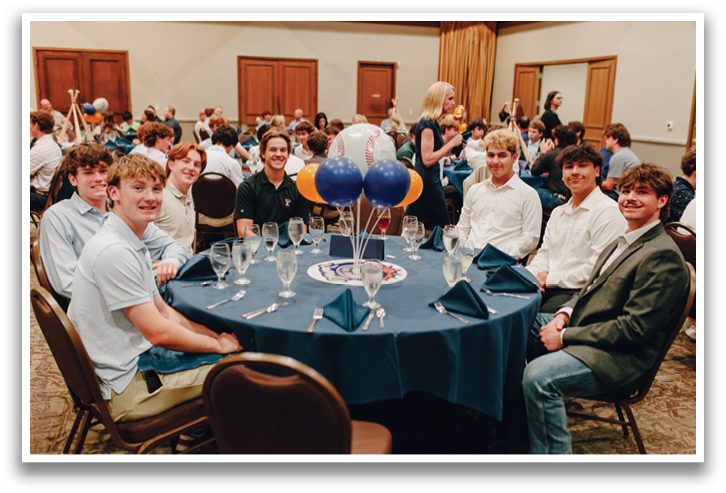 A group of young men are sitting around a table with a blue tablecloth, enjoying a meal together. Contenido generado con IA